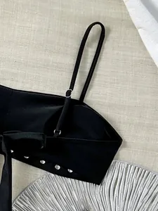 Gedetailleerd zijaanzicht van een zwarte bandeau-bikinitop met zilveren metalen studs.