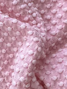 Detailed macro shot of pink textured bikini fabric with 3D raised pom pom patterns.