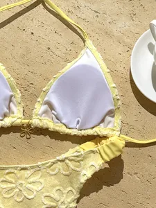 Detalle de cerca de un bikini amarillo bordado con flores que muestra encaje y relleno suave