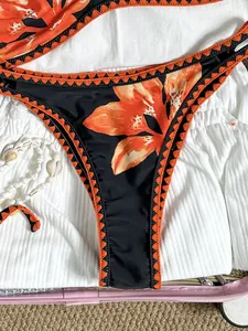 Nahaufnahme einer Vintage-Bikinihose mit Blumenmuster und orangefarbenen Stickereien.