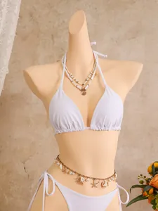 Gedetailleerd beeld van een witte halter bikini set met schelpenketting en zeester tailleketting