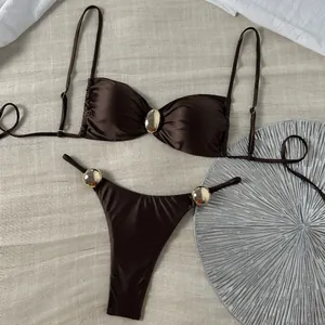 Detaillierte Ansicht eines schokobraunen glänzenden Bikinis mit goldenen Details