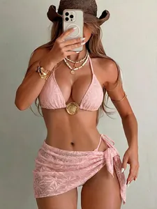 Detailopname van een driedelige roze kanten bikini-set met een bijpassende opengewerkte wikkelrok.