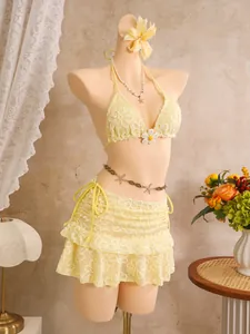 Detailansicht des gelben, floral bestickten dreiteiligen Bikini-Sets mit Rock auf Puppe.