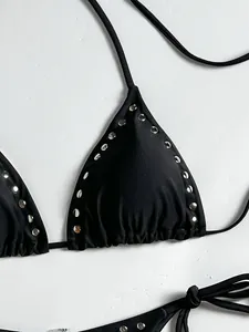Close-up detail showing black triangle bikini top with metallic silver rivet stud embellishments