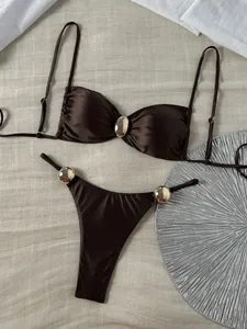 Detailansicht des glänzenden braunen Bikinis mit eleganten goldenen Metallakzenten