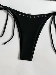 Detail view of black bikini bottom featuring silver metal studs and adjustable side ties