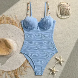 Detalle de traje de baño azul claro con copas de concha y tirantes de cuentas