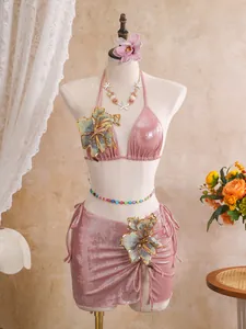 Detailed view of shiny pink three-piece bikini set with embroidered floral appliques