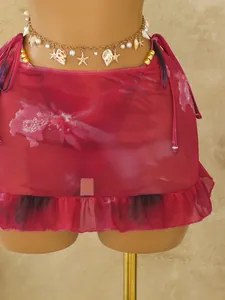 Detail van rode gebloemde mesh bikini cover-up rok met ruches en schelp buikketting