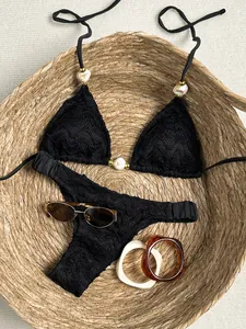 Sexy zwarte bikini-set met textuur en marmeren kralen in een mooie gevlochten mand