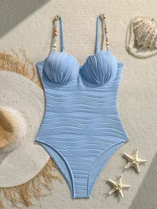Detalle de un bañador retro azul claro de una pieza con textura ondulada y copas de concha.