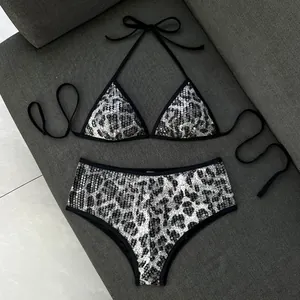 Bikini due pezzi leopardato con paillettes e slip boyleg a vita alta su sfondo grigio