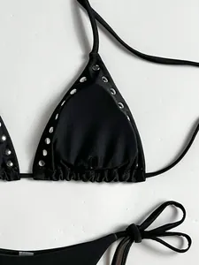 Detail shot of black halter bikini top with silver metal rivets and tie strings.
