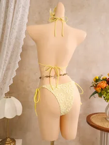 Rückansicht eines gelben Bikinis mit Blumenstickerei und einer Muschel-Tailienkette.