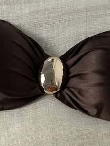 Nahaufnahme eines glänzenden braunen trägerlosen Bikini-Tops mit einer Metallschnalle.