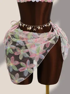 Vue détaillée des broderies florales et des paillettes sur le paréo de bikini en résille