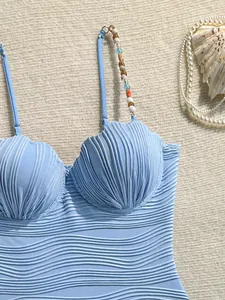 Primer plano detallado de un bañador azul con copas de concha y tiras de cuentas