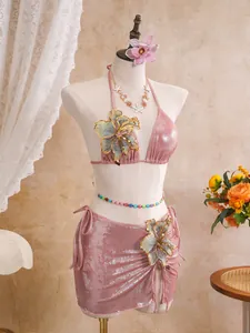 Detail of pink shimmering three-piece swimsuit featuring large floral embroidery accents.