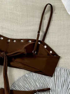 Detail van een bruine bikinitop met zilveren klinknagels en bandje