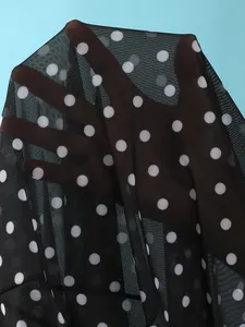 Detail van zwarte semi-transparante mesh-stof met witte stippen voor zwemkleding.
