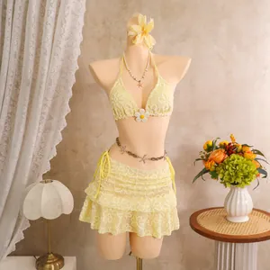 Detailansicht eines gelben, blumig bestickten dreiteiligen Bikinisets mit einem Strandrock