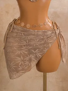 Detail van een beige gehaakte kanten sarong wrap met een elegante gouden munt buikketting