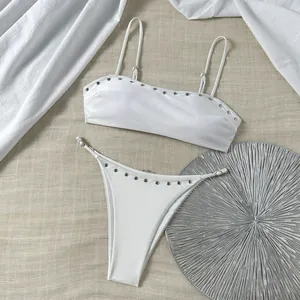 Detail van witte bandeau bikini met zilveren klinknagels op de top en het broekje.