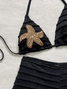 Gros plan du haut de bikini noir à volants avec détail d'étoile de mer en paillettes.