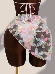 Détail d'un paréo de plage en mesh brodé de fleurs avec des paillettes étincelantes