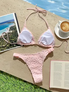 Detalle de un bikini rosa con bordado floral sofisticado junto a una piscina soleada