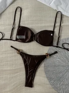 Detailansicht eines braunen glänzenden Bikinis mit goldfarbenen Metalldetails