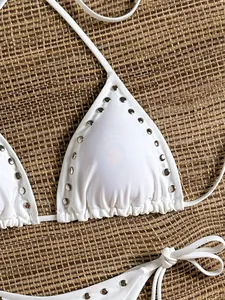 Detailed macro view of white triangle bikini top featuring silver metal rivet studs