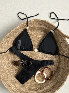 Detailopname van een zwarte getextureerde bikini met kralen in een rieten mandje
