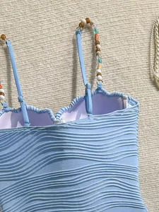 Detalle de la textura ondulada y tirantes de cuentas en este traje de baño azul