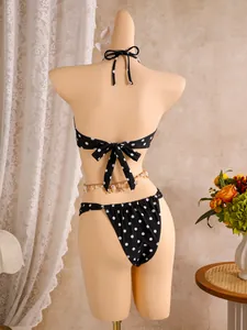 Gedetailleerd achteraanzicht van zwarte polka dot bikini met schelpen tailleketting.