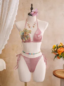 Detail view of a pink shimmering bikini set featuring an intricate embroidered flower