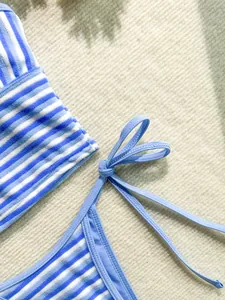 Primer plano de bikini de rizo a rayas azules y blancas con detalle de lazo y textura.