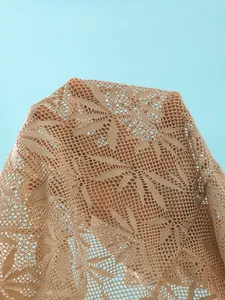 Detailopname van beige gehaakte kantstof met bladpatroon voor zomerse strandset.