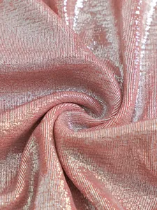 Close-up of shimmering rose gold metallic fabric with a fine sparkle texture for swimwear.