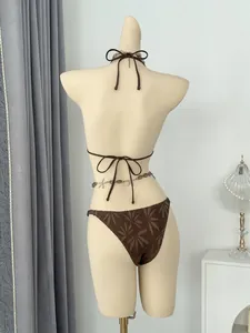Back view of brown leaf pattern bikini set on mannequin with decorative chain