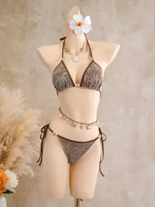 Détail d'un bikini en maille marron avec motif feuille et ornements en coquillage sur mannequin.