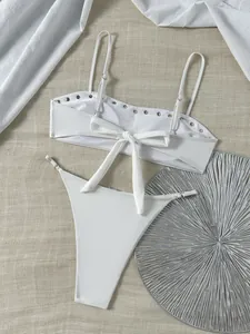 Gedetailleerde weergave van witte bikini met zilveren studs en strik