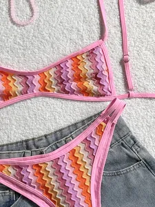 Primer plano de bikini bohemio de ganchillo retro con patrón de zigzag sobre denim.