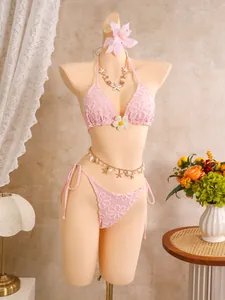 Detailansicht des rosa bestickten Bikinis mit Muschel-Accessoires am Strand