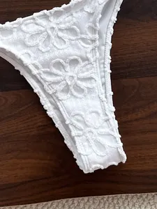 Detalle del bordado floral blanco y la textura de encaje de la braguita del bikini