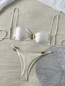 Detailansicht eines cremefarbenen glänzenden Satin-Bandeau-Bikinis mit eleganten Goldverzierungen
