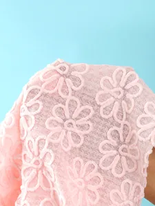 Nahaufnahme des weichrosa strukturierten Stoffes mit Blumenstickerei für Strandkleid