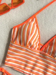 Primer plano detallado de un top de bikini de rayas naranjas y blancas en tela de toalla
