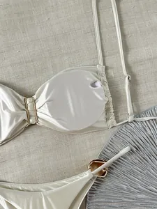 Nahaufnahme des weißen Ölglanz-Satin-Bikini-Sets mit eleganten Goldring-Metallteilen